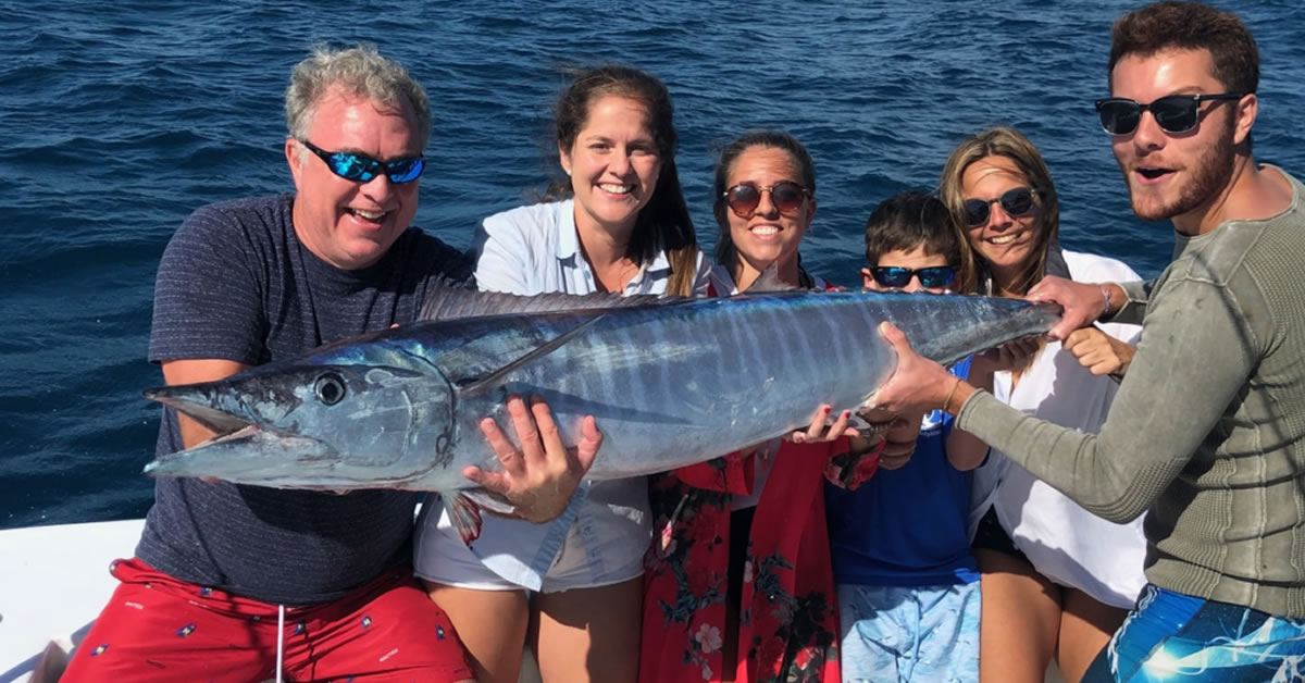 Happy family posing with a Wahoo aboard Main Attraction vessel